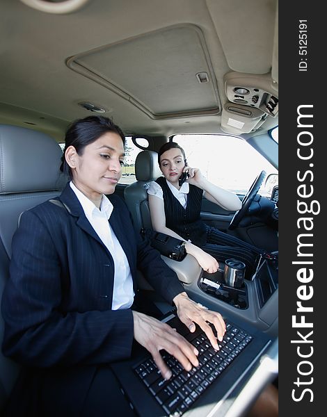 Two businesswomen working on a laptop in a mobile office in a car. Two businesswomen working on a laptop in a mobile office in a car