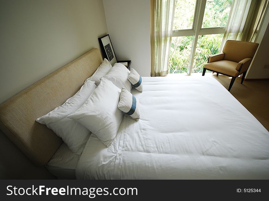 Comfortable bedroom with neatly made white bed. Comfortable bedroom with neatly made white bed.