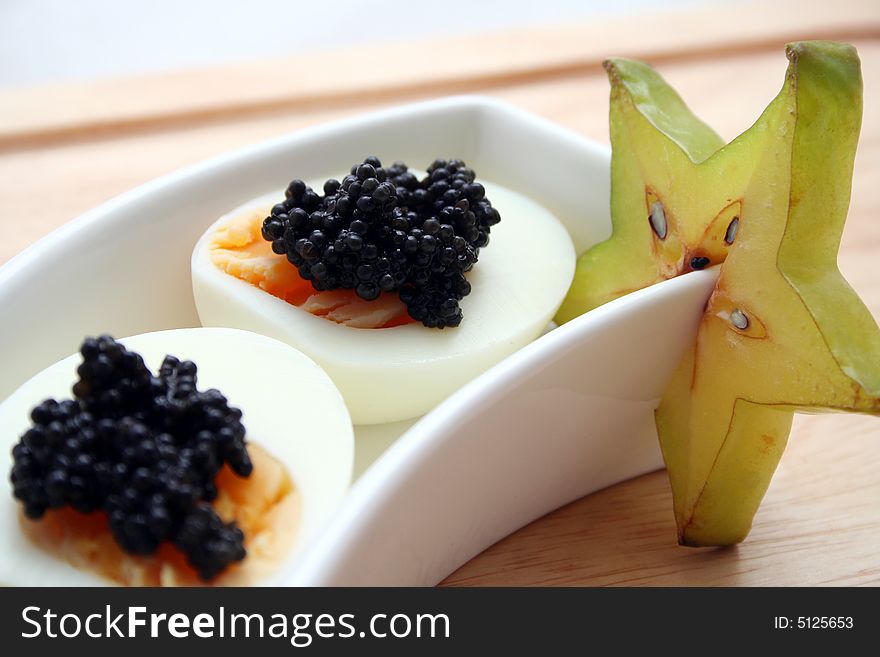 Two eggs with caviar and starfruit decoration