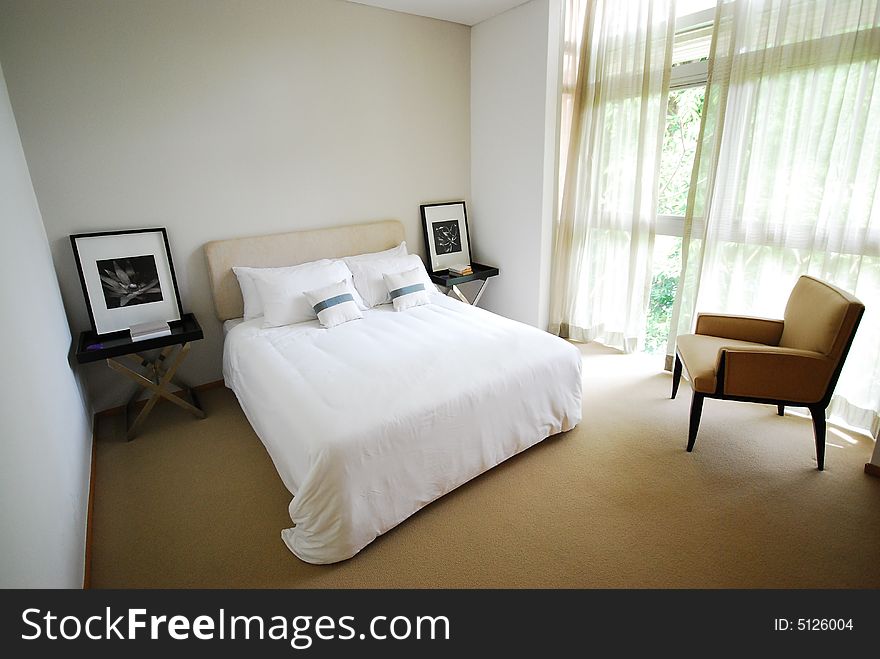 Comfortable bedroom with neatly made white bed. Comfortable bedroom with neatly made white bed.