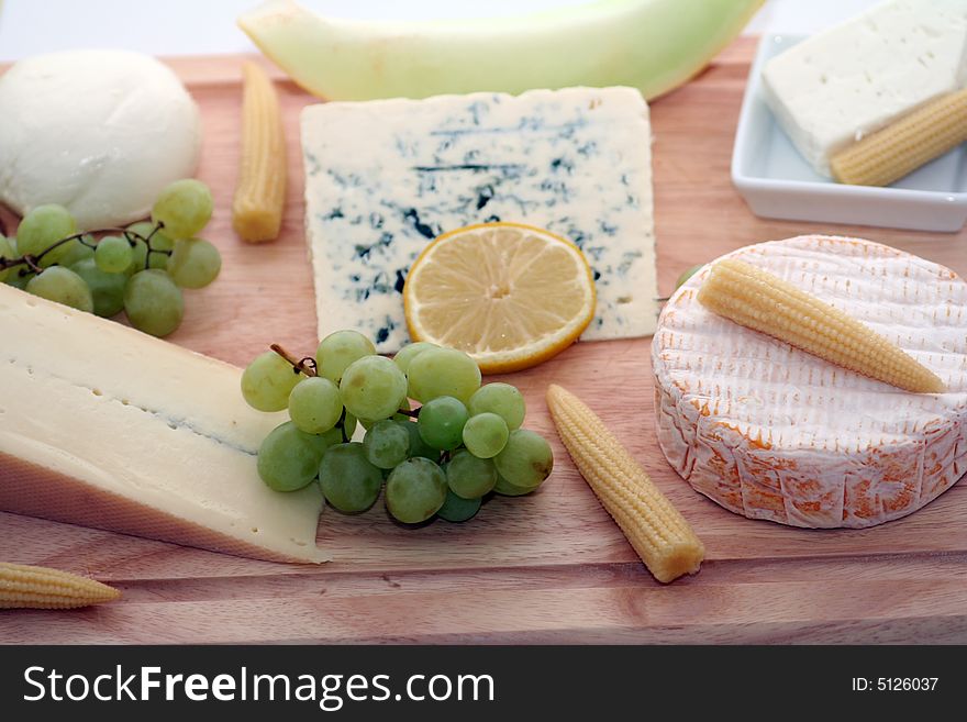 A wodden plate with a lot of different cheeses