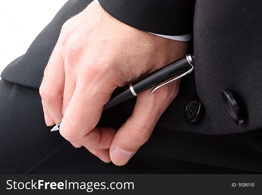 Close up of a person's hand in a black suit holding a pen. Close up of a person's hand in a black suit holding a pen