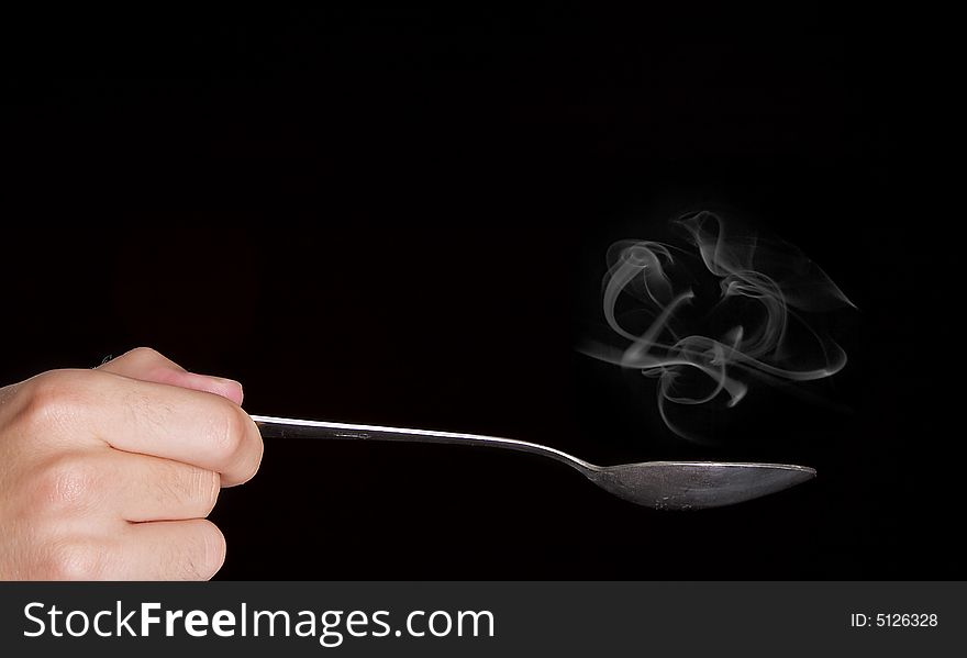 Smoking old spoon over black background