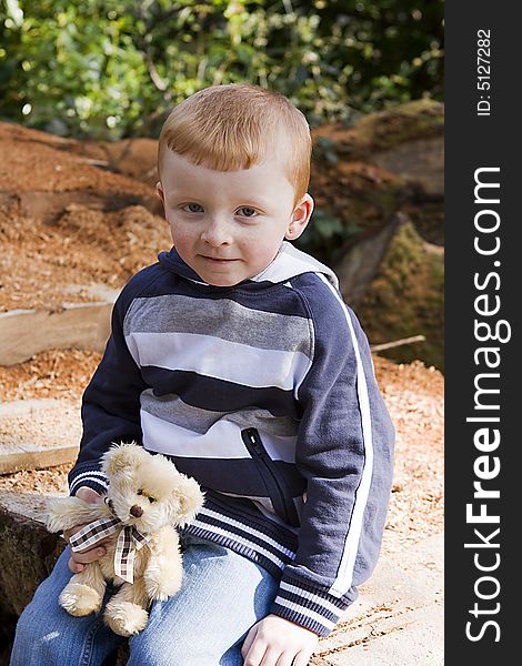 Boy with his teddy bear looking happy and content