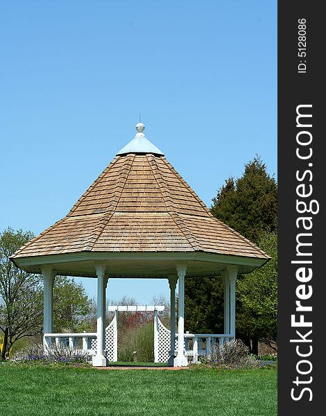 A White gazebo in a park with blue sky