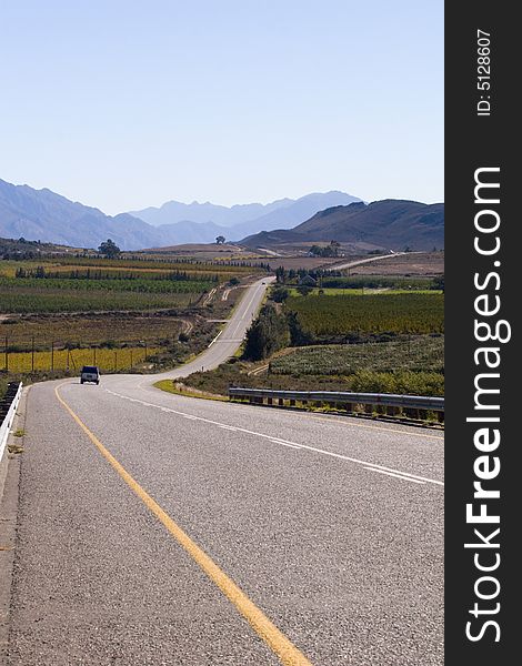 A country road through the mountains on a clear day with blue sky. A country road through the mountains on a clear day with blue sky