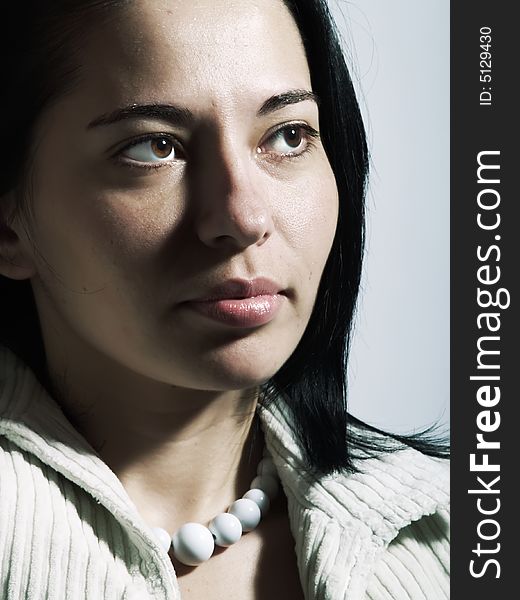 A high-key portrait about an attractive trendy lady with black hair who is looking at something and she has a charming look. She is wearing a white coat and a white necklace. A high-key portrait about an attractive trendy lady with black hair who is looking at something and she has a charming look. She is wearing a white coat and a white necklace.