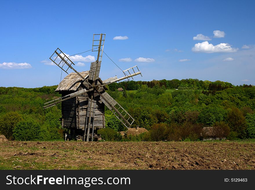 Windmill With Fresh Green Grass And Clear Blue Sky