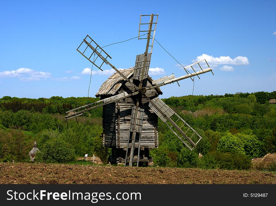 Windmill With Fresh Green Grass And Clear Blue Sky