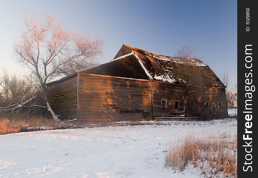 Shadows of trees paint a barn in a winter sunset. Shadows of trees paint a barn in a winter sunset.
