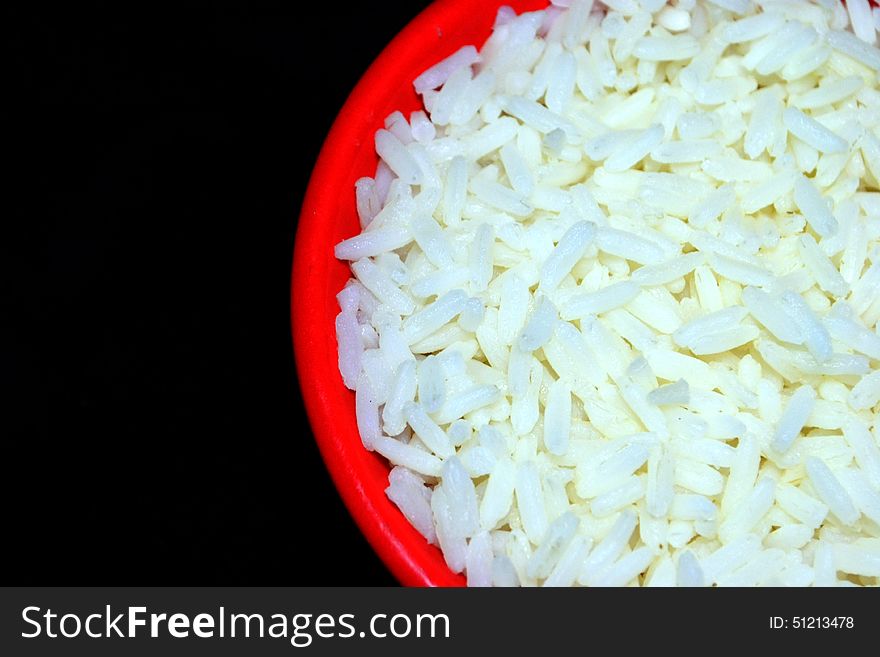 White rice on red plate with black background. White rice on red plate with black background.