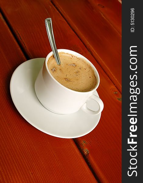 Cappuccino cup with spoon on wood background. Cappuccino cup with spoon on wood background