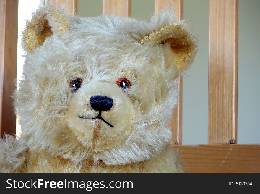 An antique well loved toy teddy bear sits in a wooden kitchen chair. An antique well loved toy teddy bear sits in a wooden kitchen chair.