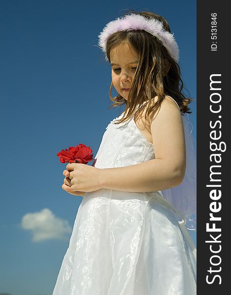 Little girl holding red roses against blue sky and a cloud