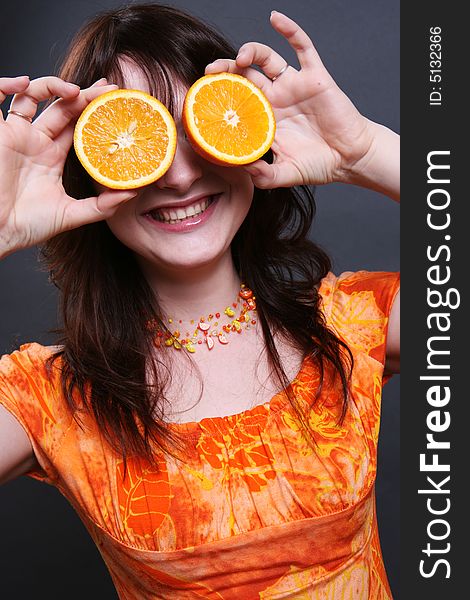 The positive smiling girl with an orange in hands. The positive smiling girl with an orange in hands