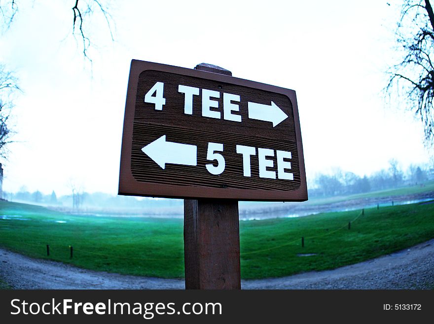 Tee sign directing carts on a golf course to the various holes.  Green visible behind sign. Tee sign directing carts on a golf course to the various holes.  Green visible behind sign.