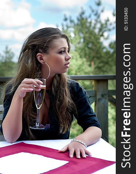 Young girl with glass of champagne on veranda
