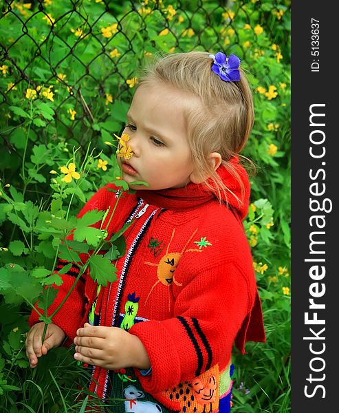 Little girl walks in the spring on a young grass in park