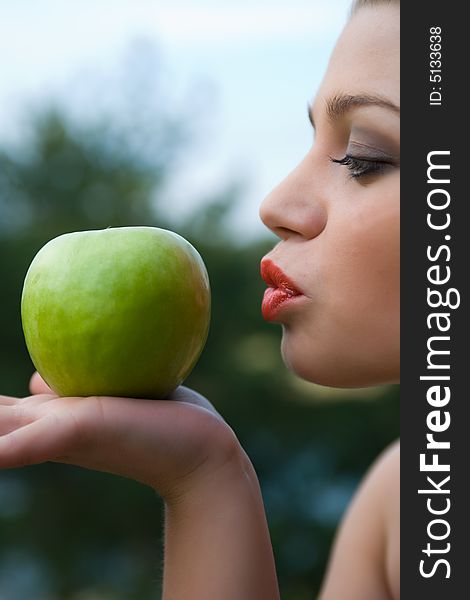 Girl with apple on sunset on green background