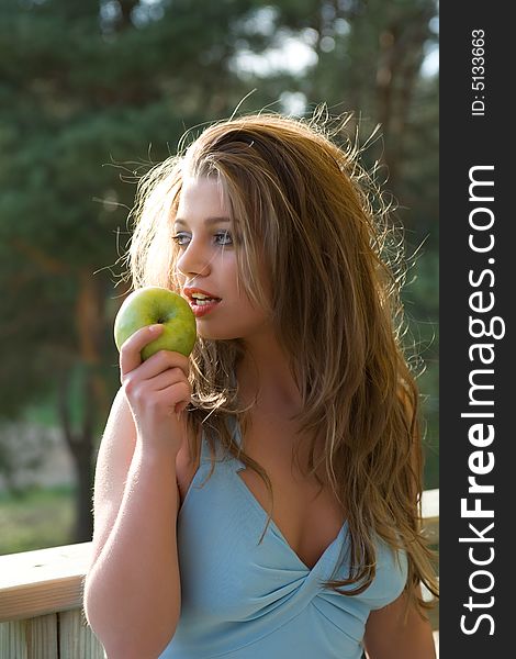 Girl with apple on sunset on green background