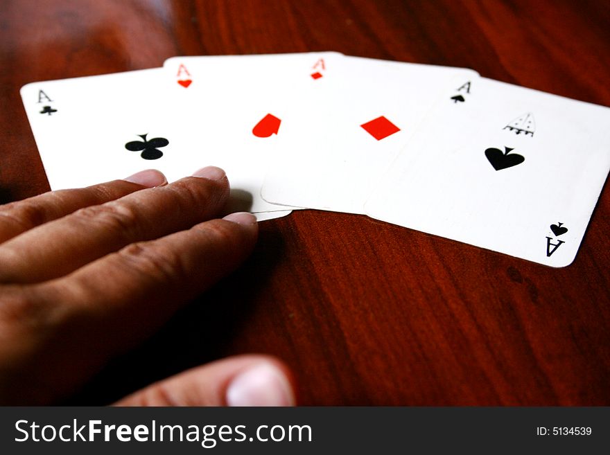 An image of four aces in a table with a person's hand. An image of four aces in a table with a person's hand.