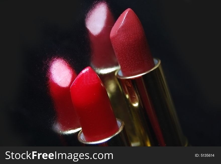 Two lipsticks with its reflection on black