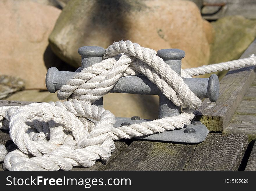 White rope tied to the cleat at the dock. White rope tied to the cleat at the dock