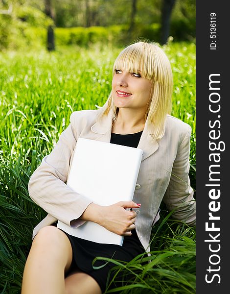 Smiling student with laptop on the grass. Smiling student with laptop on the grass