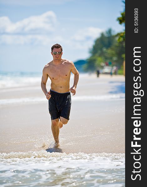 Caucasian man running on the beach with sunglasses. Caucasian man running on the beach with sunglasses