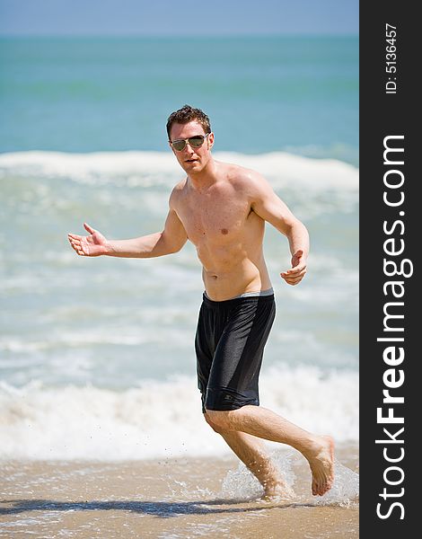 Caucasian man running on the beach with sunglasses. Caucasian man running on the beach with sunglasses