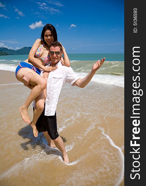 Young multiethnic couple enjoying themselves on a beautiful day at the beach. Young multiethnic couple enjoying themselves on a beautiful day at the beach