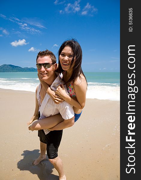 Caucasian hunk carrying a gorgeous asian woman on his back having lots of fun. Caucasian hunk carrying a gorgeous asian woman on his back having lots of fun