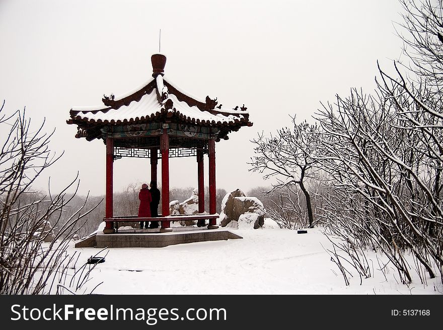 A couple standing on a gloriette after snow