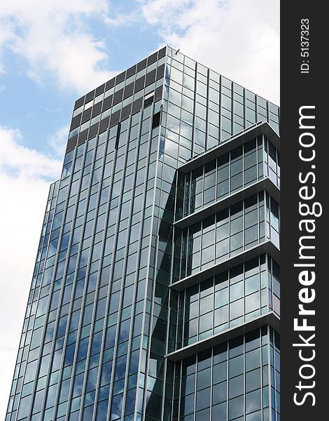 Modern office building with reflection of cloudy sky. Vertical perspective.