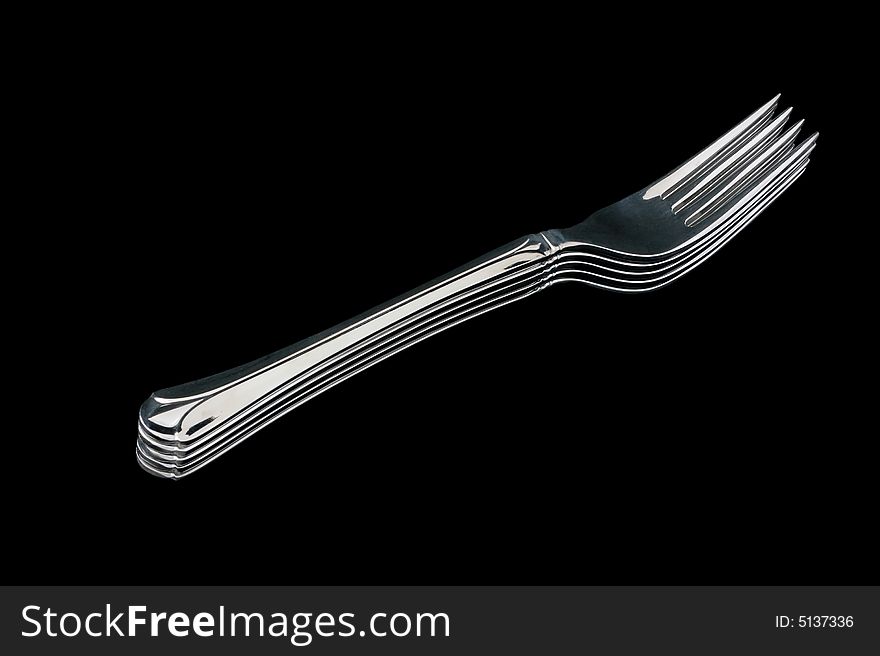 A pile of five silver forks, isolated on black