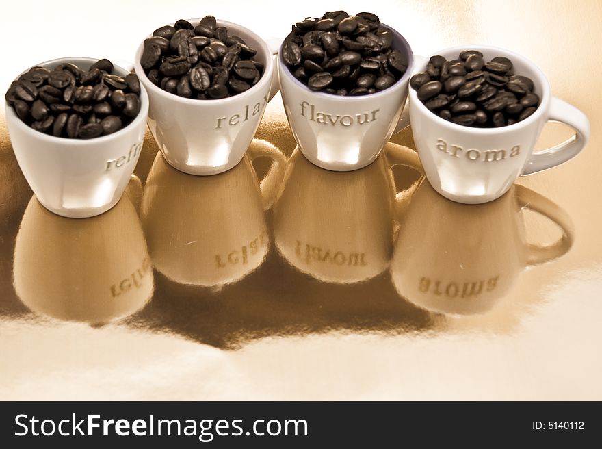 Four coffee cups filled with fresh roasted coffee beans on reflected background. Four coffee cups filled with fresh roasted coffee beans on reflected background