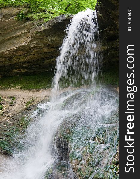 Small rocky waterfall in the forest, motion blur