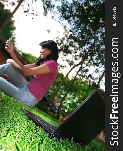 laptop with girl holding cellphone at background in nature. laptop with girl holding cellphone at background in nature