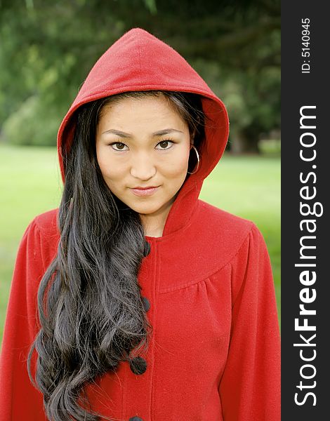 Young Asian girl in a bright red coat with hood. Young Asian girl in a bright red coat with hood