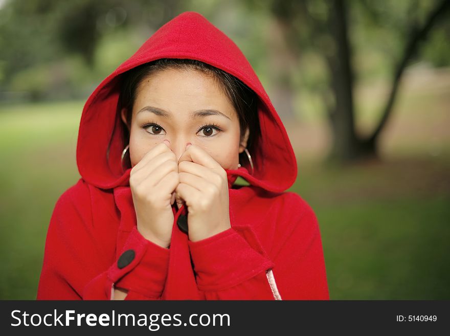Young Asian girl in a bright red coat with hood. Young Asian girl in a bright red coat with hood