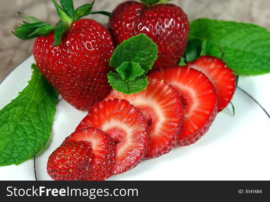 Fresh whole and sliced Strawberries on a white plate. Fresh whole and sliced Strawberries on a white plate.