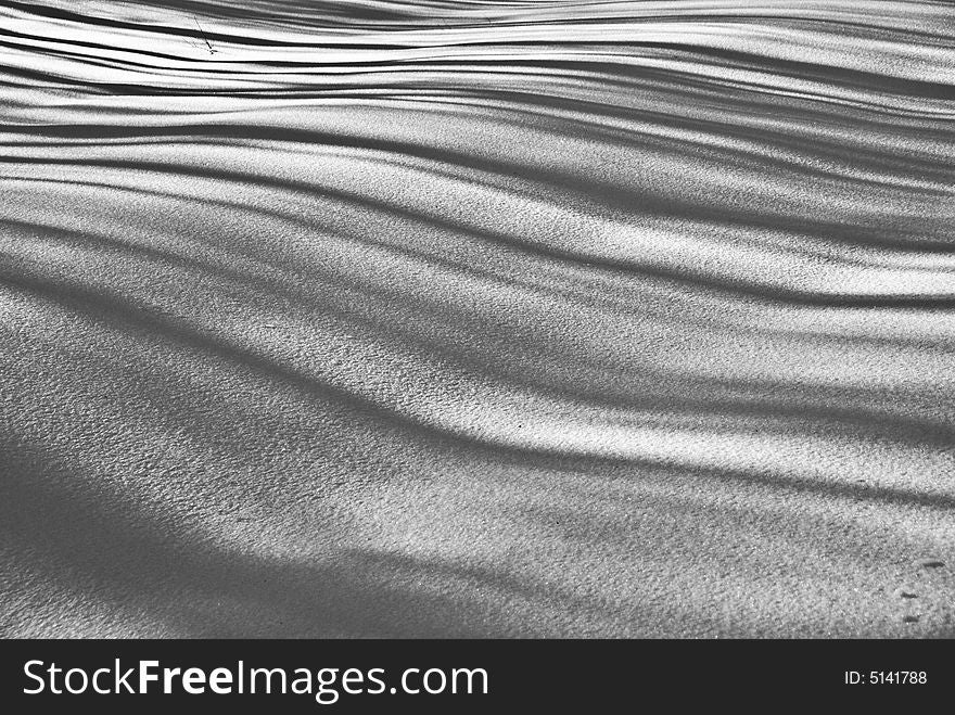 Shadows fall in rippling lines across a rolling snowscape. Shadows fall in rippling lines across a rolling snowscape