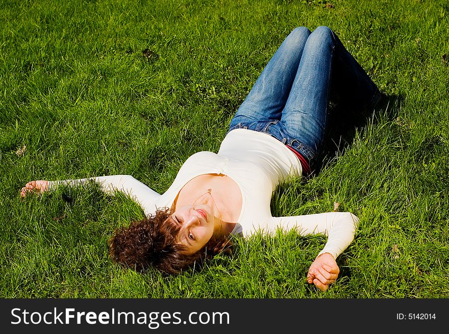Looking to camera beauty girl with big breast is smiling and relaxing on the grass. Looking to camera beauty girl with big breast is smiling and relaxing on the grass