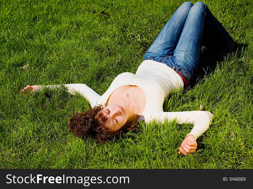 Looking to camera beauty girl with big breast is smiling and relaxing on the grass. Looking to camera beauty girl with big breast is smiling and relaxing on the grass