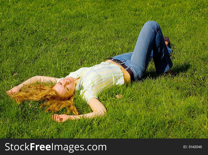 Beauty girl is smiling and relaxing on the grass. Beauty girl is smiling and relaxing on the grass