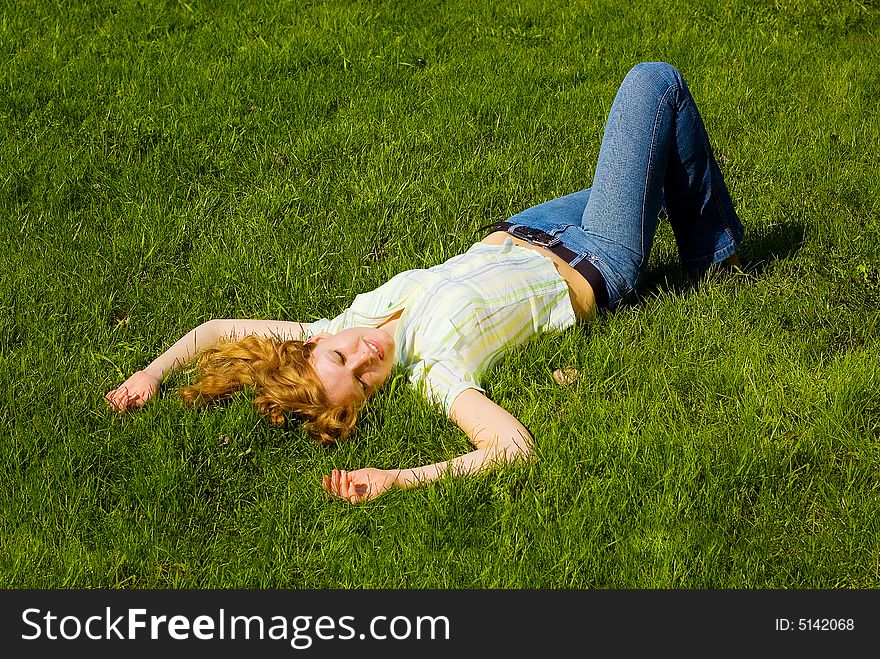 Beauty girl is smiling and relaxing on the grass. Beauty girl is smiling and relaxing on the grass