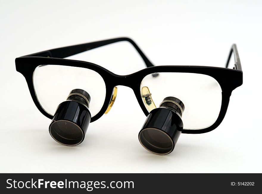 A pair of magnifying glasses for surgical use with the earpieces propped open. A pair of magnifying glasses for surgical use with the earpieces propped open.