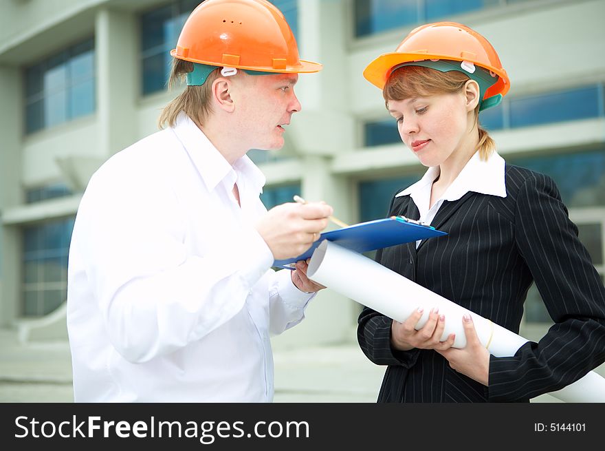 Architects man and woman protective helmet standing in front of a building