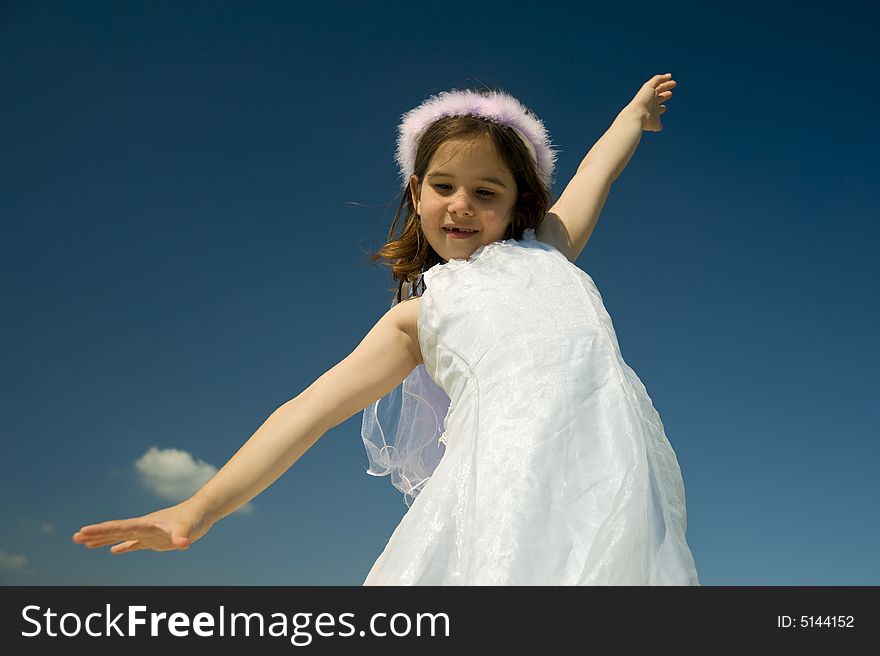 Young girl with spreads arms against blue sky. Young girl with spreads arms against blue sky