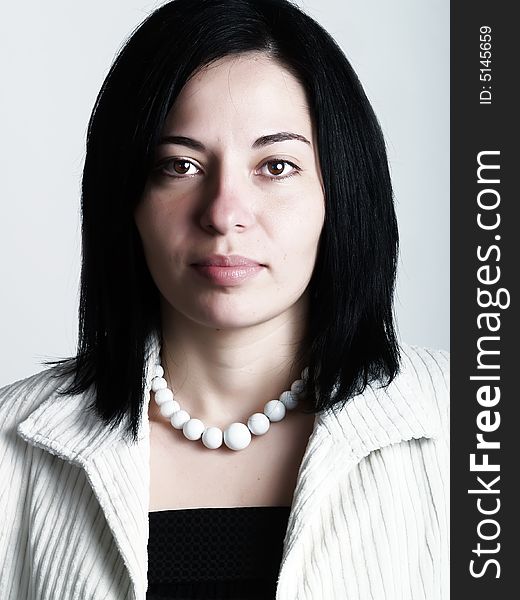 A high-key portrait about a pretty trendy lady with black hair who is looking ahead and she has an attractive look. She is wearing a white coat, a black dress and a white necklace. A high-key portrait about a pretty trendy lady with black hair who is looking ahead and she has an attractive look. She is wearing a white coat, a black dress and a white necklace.